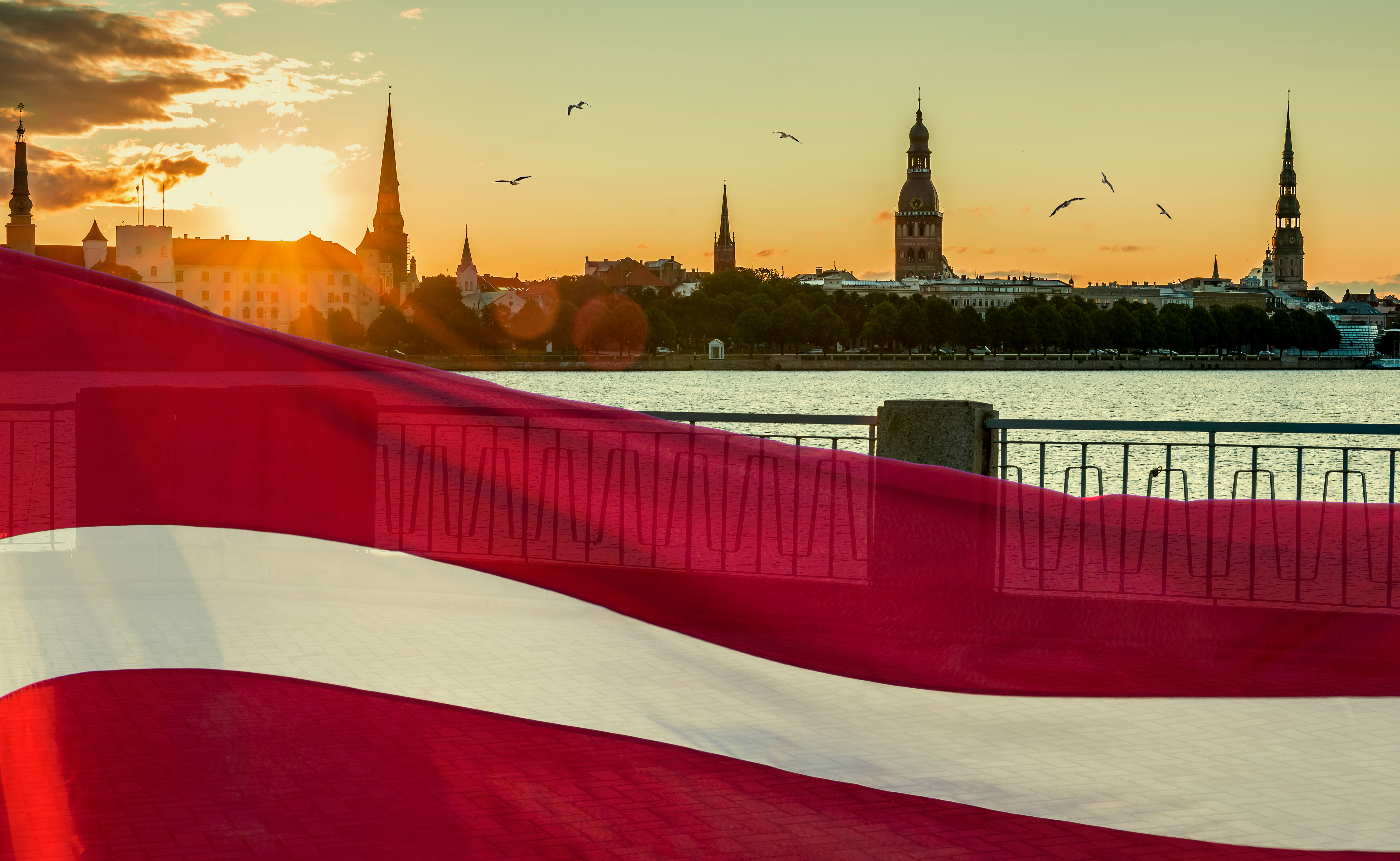 Флаг Латвии на фоне Риги, где иностранцы могут купить недвижимость
