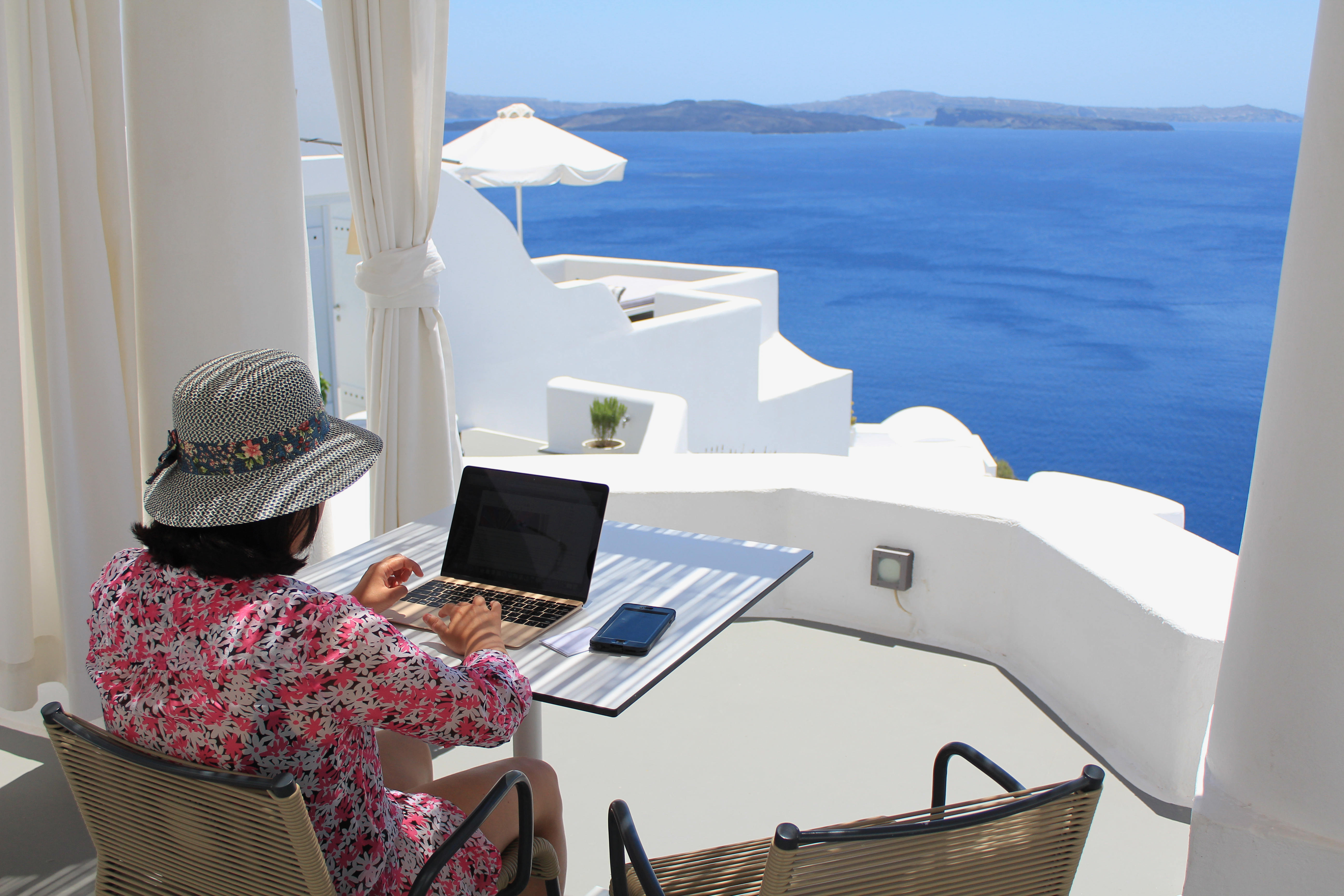 Девушка с ноутбуком в Санторини, в Греции, работа в которой доступна для русских, украинцев и белорусов