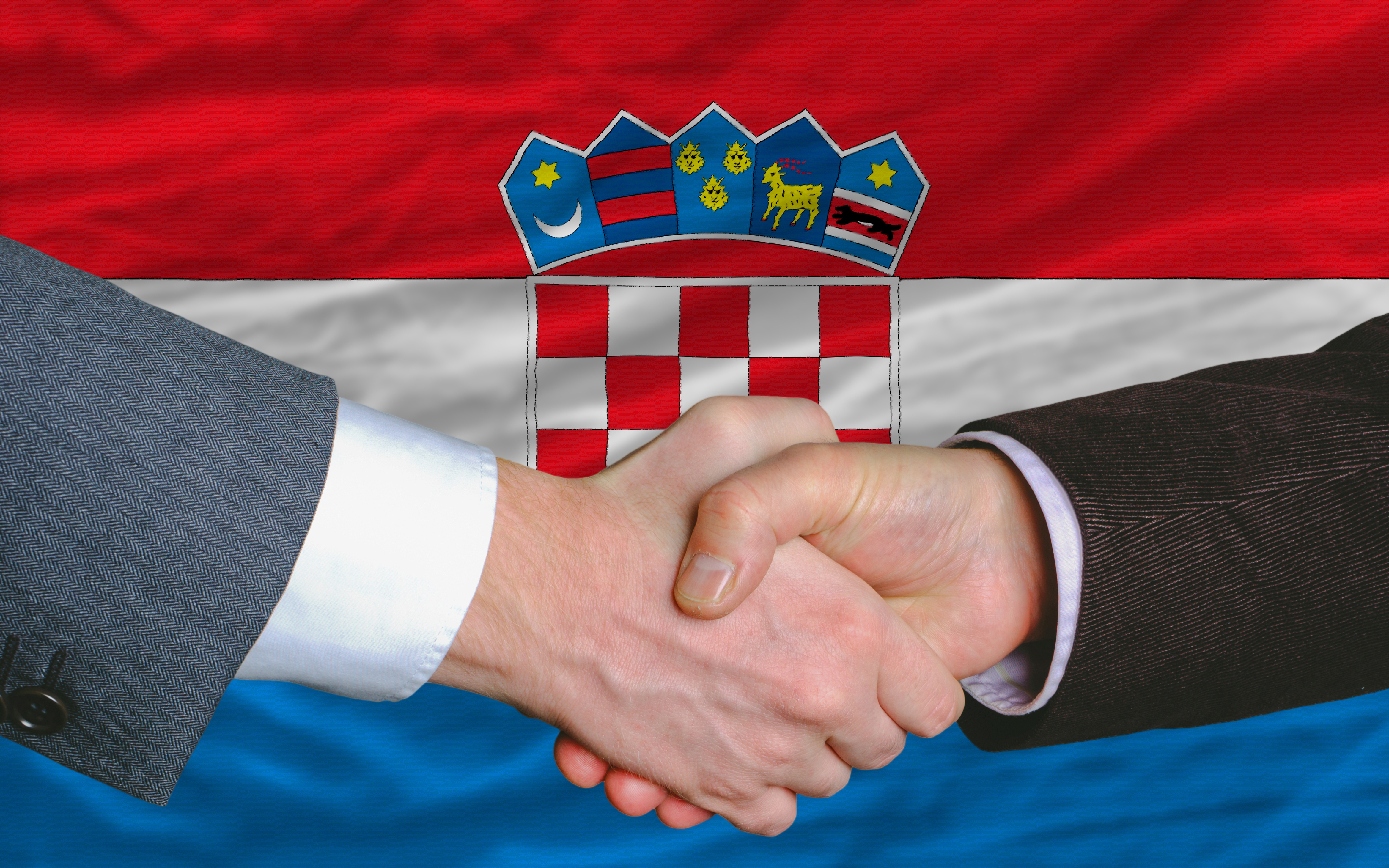 Рукопожатие на фоне флага Хорватии, куда можно переехать по трудоустройству